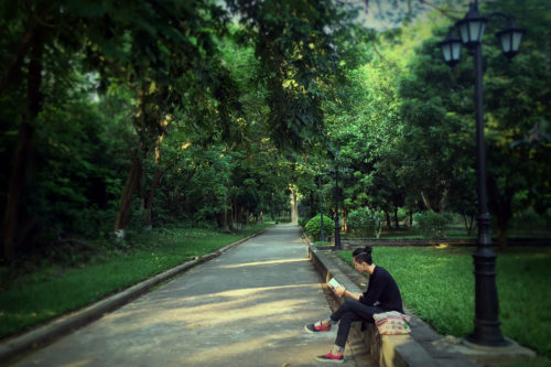 道端に腰かけて読書する男性